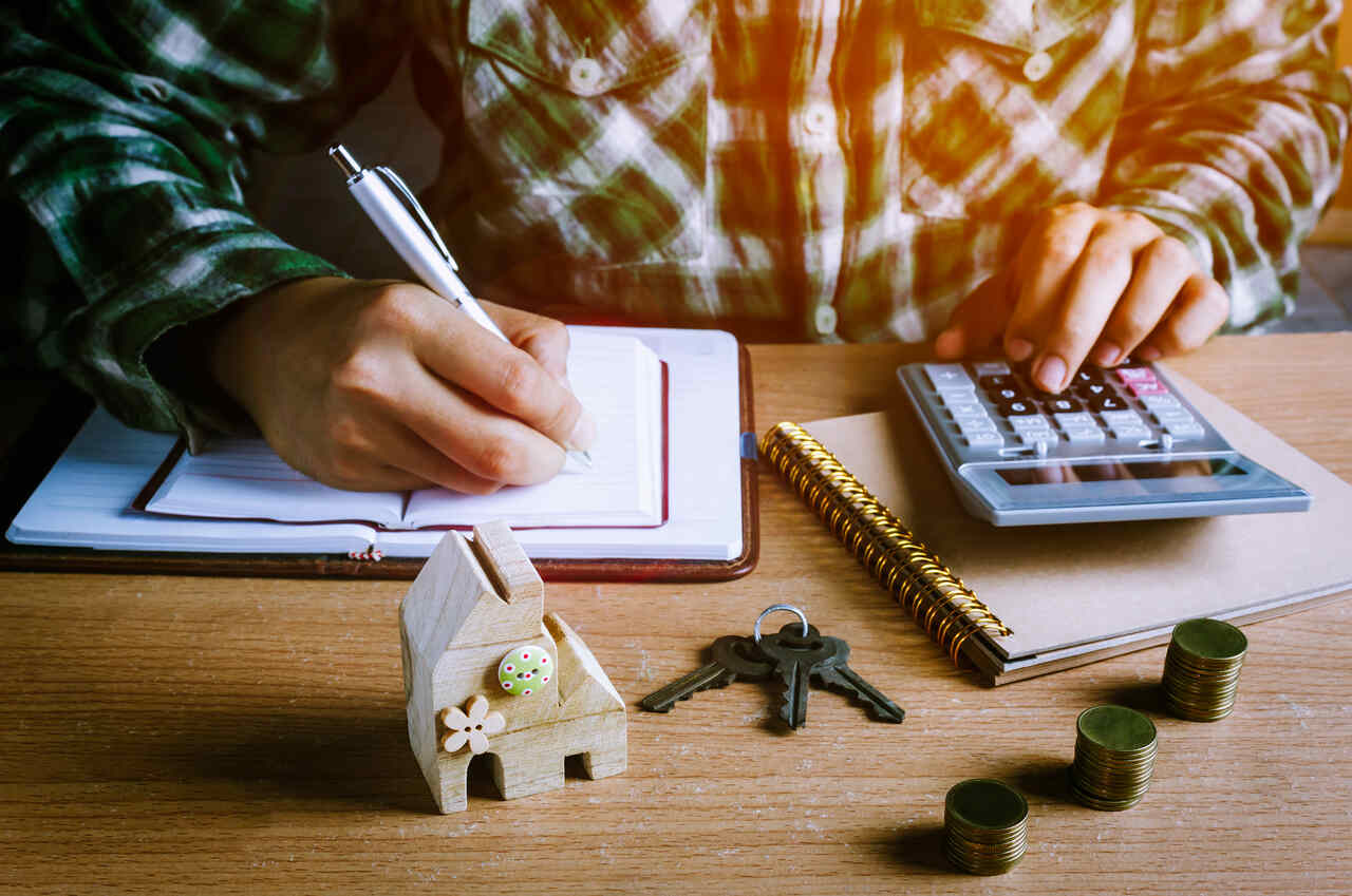 Homem com calculadora, chaves, moedas, caneta e agendas analisa herança 