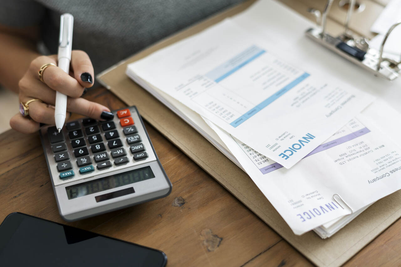 mulher com caneta, calculadora e folhas de pagamento Imposto de Renda 2024